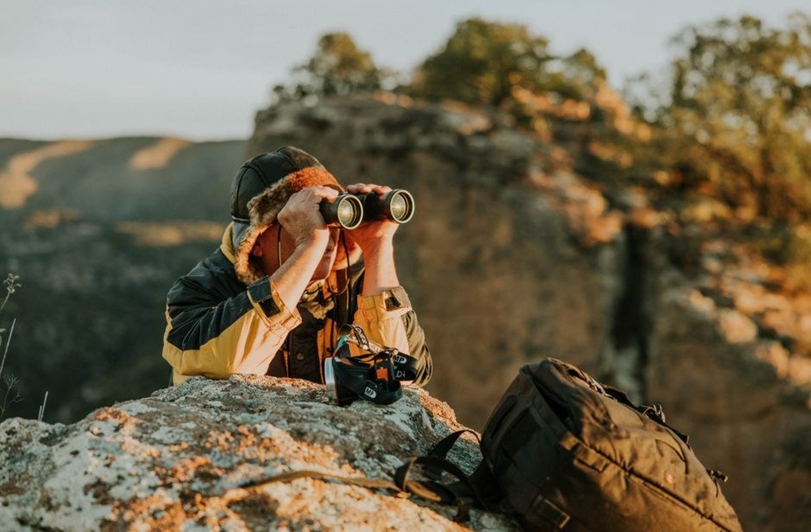Photographer outdoors with a camera, looking across a familiar landscape.